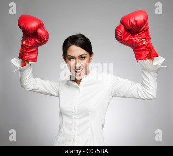 Imprenditrice in guantoni da pugilato tifo con le braccia sollevate Foto Stock