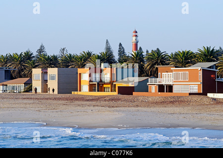 Case colorate sulla spiaggia di Swakopmund, nella parte posteriore del faro storico, Regione di Erongo, Namibia, Africa Foto Stock