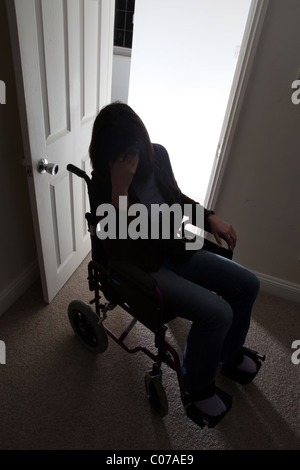 Una donna su una sedia a rotelle con la mano alla sua testa. Foto Stock
