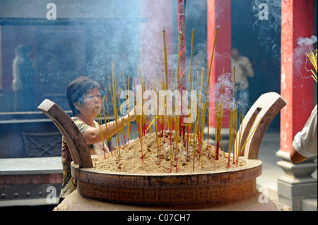 Credendo donna sacrificare i bastoncini di incenso nel tempio Cinese, Chua Thien Hau Pagoda, Cho Lon, Chinatown, la città di Ho Chi Minh Foto Stock