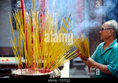 Uomo con bastoncini di incenso nel tempio Cinese, Chua Thien Hau Pagoda, Cho Lon, Chinatown, Ho Chi Minh City, a Saigon, Vietnam del Sud Foto Stock