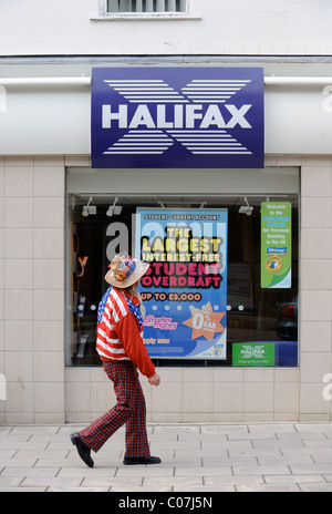 Un vestito in maniera colorata passer da al di fuori di una filiale della Halifax Bank a Cheltenham Regno Unito Foto Stock