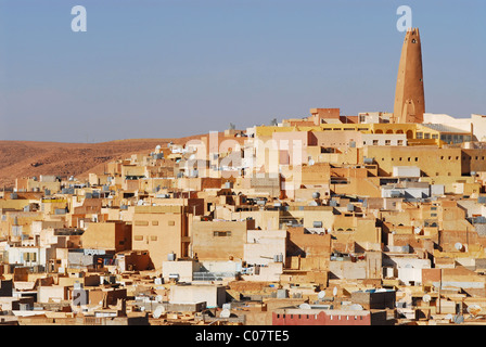 Algeria, Ghardaia, vista città con mattoni di fango e di abitazione minareto alto contro il cielo chiaro Foto Stock