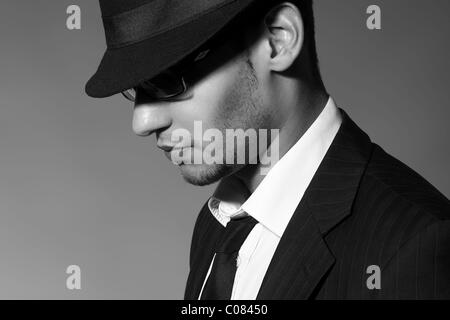 Lato ritratto di un giovane uomo con occhiali, suit, camicia e cravatta e hat Foto Stock