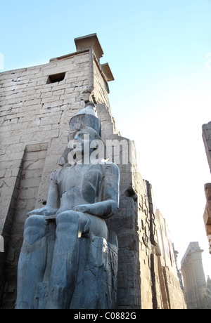 Un antico e storico egiziano grande statua sta di guardia all'entrata del tempio di Luxor a Luxor, Egitto Foto Stock