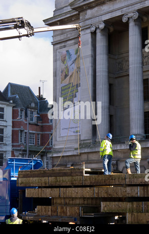 Operai lavorano con una gru e il carrello per preparare nottingham piazza del mercato per la fiera del divertimento a scuola a metà termine febbraio 2011 Foto Stock