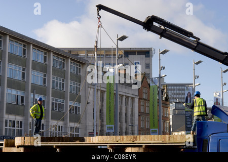 Operai lavorano con una gru e il carrello per preparare nottingham piazza del mercato per la fiera del divertimento a scuola a metà termine febbraio 2011 Foto Stock