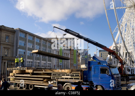 Operai lavorano con una gru e il carrello per preparare nottingham piazza del mercato per la fiera del divertimento a scuola a metà termine febbraio 2011 Foto Stock