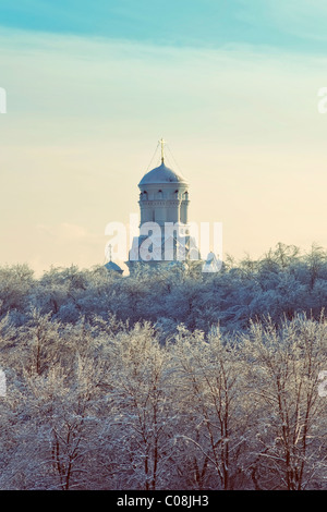 Incantevole paesaggio invernale con la foresta coperta di neve e il cristiano-ortodossa contro il cielo Foto Stock
