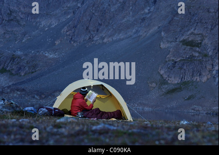 La donna in una tenda consulta un gps e mappa mentre campeggio Al Lago di coniglio, Chugach State Park, centromeridionale Alaska, Autunno Foto Stock