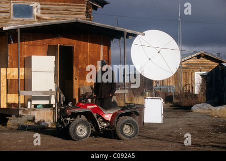 Uomo nativa sorge accanto a un ATV su una giornata autunnale nel villaggio di artico, Arctic Alaska Foto Stock