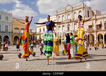 Un gruppo di artisti di strada o gli artisti interpreti o esecutori in passerella su palafitte a piedi attraverso le strade di La Habana, Cuba in luminosi colorati costumi Foto Stock