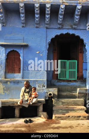 Uomo anziano con un bambino sul banco di pietra di fronte a casa sua, Jodhpur, Rajasthan, India, Asia Foto Stock