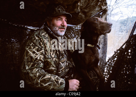 Cacciatore con il cioccolato Labrador Retriever in una cieca a Hardy lago nella contea di Scott, Indiana Foto Stock