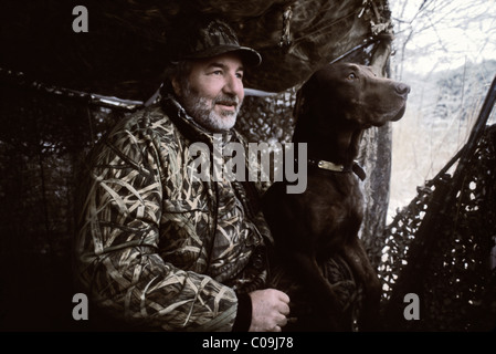 Cacciatore con il cioccolato Labrador Retriever in una cieca a Hardy lago nella contea di Scott, Indiana Foto Stock