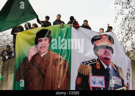 Pro i sostenitori di Gheddafi tenere premuto su enormi manifesti in Ambasciata libica di dimostrazione Foto Stock