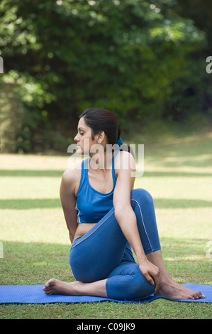 Donna facendo Ardha Matsyendrasana (Mezza torsione spinale) Foto Stock