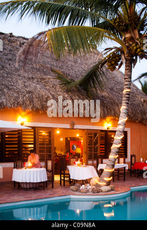 Un ristorante è accesa fino in prossimità di una piscina presso un hotel di lusso in Belize. Foto Stock