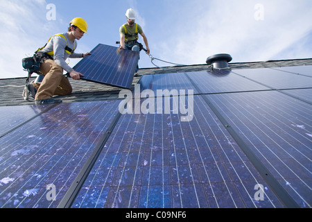 Due lavoratori installare pannelli solari su un tetto a Redmond, WA. Foto Stock
