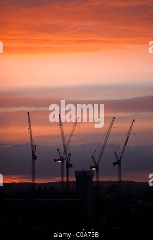 Silhouette di gru al tramonto sul sito di costruzione, Londra, Inghilterra, Regno Unito. Foto Stock