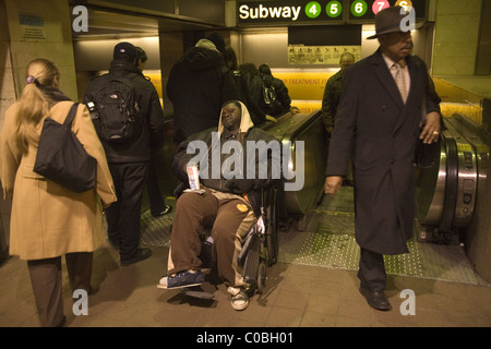 Gravemente disabili uomo in sedia a rotelle mendica per denaro presso la Grand Central Station, New York City. Foto Stock