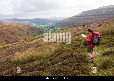 Escursionista femmina lettura mappa guardando giù Cwm Banw verso il Pan di Zucchero Montagna Nera Parco Nazionale di Brecon Beacons Wales UK Foto Stock