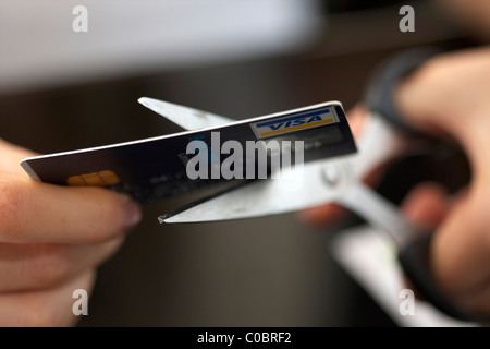 Mani femminili di taglio di una carta bancaria in due metà/ Foto Stock
