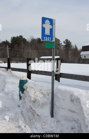 Idrante di fuoco e cartello stradale coperto di neve Foto Stock