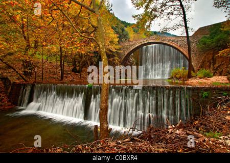Un antica pietra ponte arcuato, tra due cascate in Paleokarya, prefettura di Trikala, Tessaglia, Grecia Foto Stock