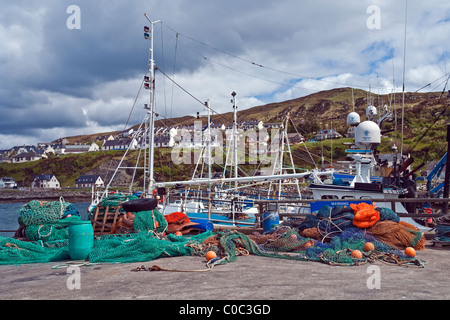 Barche da pesca ormeggiate nel porto di Mallaig nel West Highlands della Scozia con le reti da pesca in primo piano Foto Stock