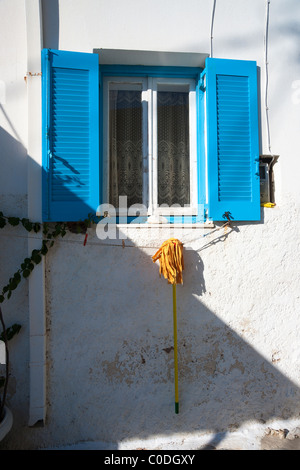 Giallo radazza appesa ad asciugare al di sotto di un blu nella finestra ritagliata su una parete esterna di una casa a Naoussa, Grecia. Foto Stock