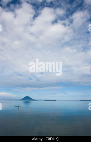 Un pescatore solitario sul mare con Bunaken Island e Pulau Manado Tua visto in lontananza Foto Stock