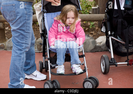 Stanco bambino si siede in un passeggino al Parco a Tema del Regno Magico di Disney World a Orlando in Florida. Foto Stock