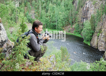Uomo felice con la fotocamera sulla parte superiore della taiga forest. Foto Stock