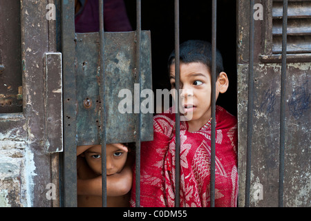 I bambini guardando attraverso il ferro battuto griglie Vecchia Havana Cuba. Foto Stock
