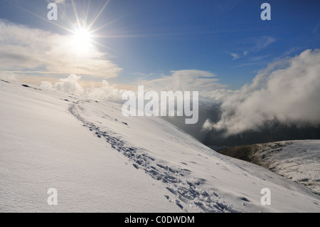 Sentiero nella neve sotto un sole invernale sul Helvellyn nel Lake District inglese Foto Stock