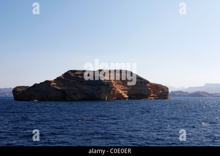 Una sterile, isola rocciosa sorge dal mare blu. Foto Stock