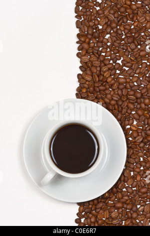 Caffè in tazza bianca sul piattino posto sullo sfondo di chicchi di caffè e bianco Foto Stock