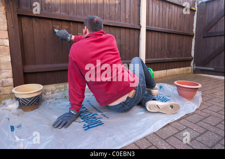 Un modello rilasciato uomo opera il suo giardino recinto con legno preserver nel Regno Unito Foto Stock