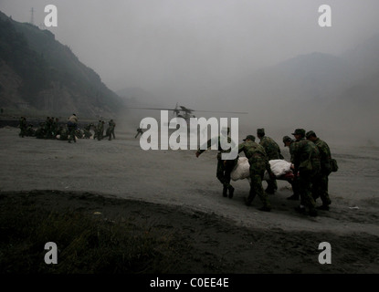 Il popolo cinese della Esercito di Liberazione (PLA) portano i soldati feriti sopravvissuti terremoto ad un elicottero di attesa in Yingxiu Foto Stock