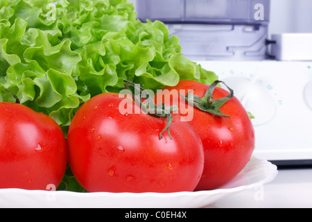 Pomodori e insalata verde foglia, cucina processore in distanza Foto Stock