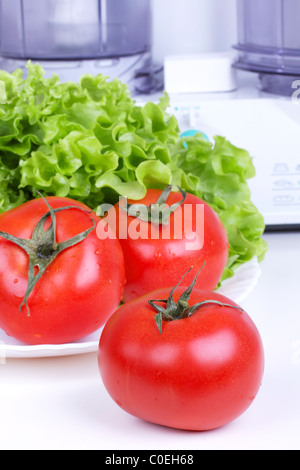 Pomodori e foglia di insalata e cucina processore sulla tavola bianco Foto Stock