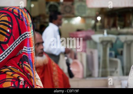 Una donna Bangadeshi con Colorati luminosamente la copertura del capo diventa il suo cercare in un bagno shop Foto Stock
