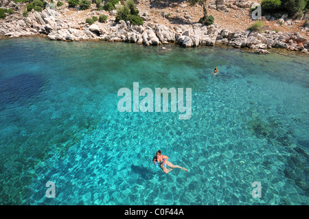 Donna nuoto nella bellissima crystal clear blu-verdi acque del mare Egeo, Turchia, Europa Foto Stock