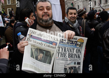 Manifestante libica tenere premuto su quotidiani che mostra la copertura dei media Foto Stock