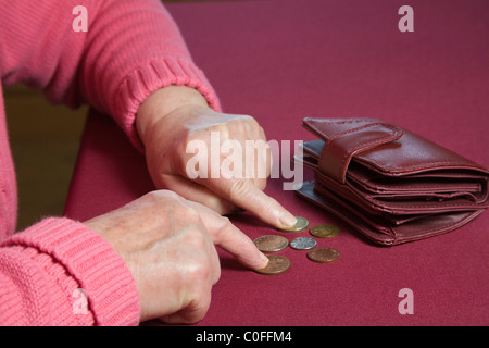 Close up donna anziana contando le poche monete al di fuori della sua borsa Foto Stock