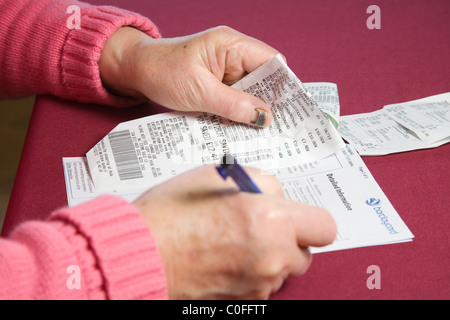 Close up donna anziana le voci di controllo sul suo Barclaycard carta di credito estratto conto Foto Stock