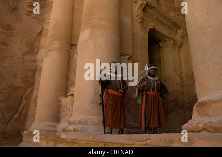 Jordanian uomini vestiti come guerrieri Nabatean presso l'ingresso all'antico El Tesoro Khazneh scolpiti nella pietra arenaria rosa situato sulla scogliera di Petra, antica capitale del regno Nabatean nel deserto sudoccidentale della Giordania Foto Stock