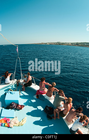 Viaggio in barca attraverso il Mar Mediterraneo, Cipro shore. Parecchie persone sedersi sulla prua della nave. Vista posteriore Foto Stock