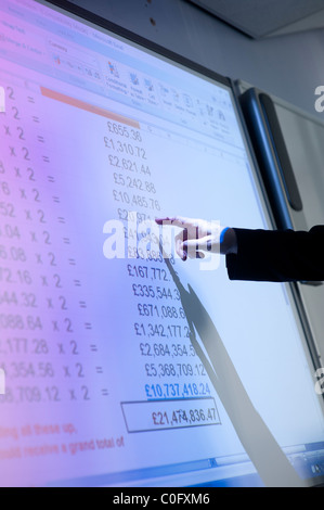 Un uomo presentando un foglio di calcolo di dati finanziari su un interactive lavagna digitale REGNO UNITO Foto Stock